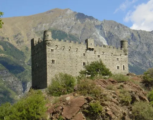 Castello di Ussel — a 14th-century square stone castle with corner turrets on a rocky outcrop, alps behind.