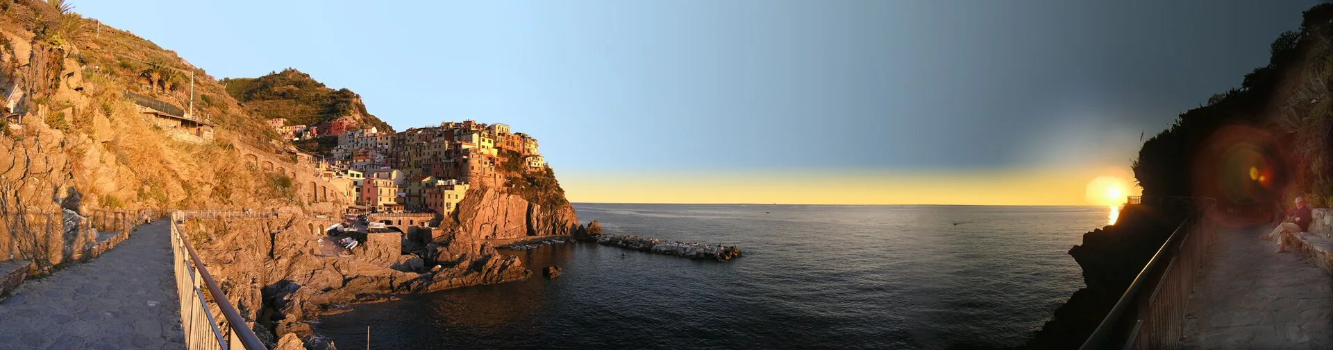 Manarola at sunset, Cinque Terre — pastel houses stacked on the cliffs above the sea, with golden-hour light over the Ligurian coast.
