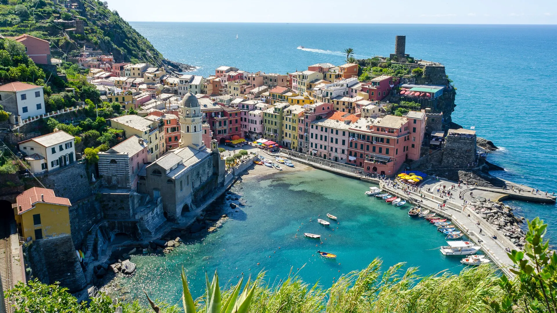 Vernazza, Cinque Terre — pastel houses curving around the natural harbour with the church and watchtower above.