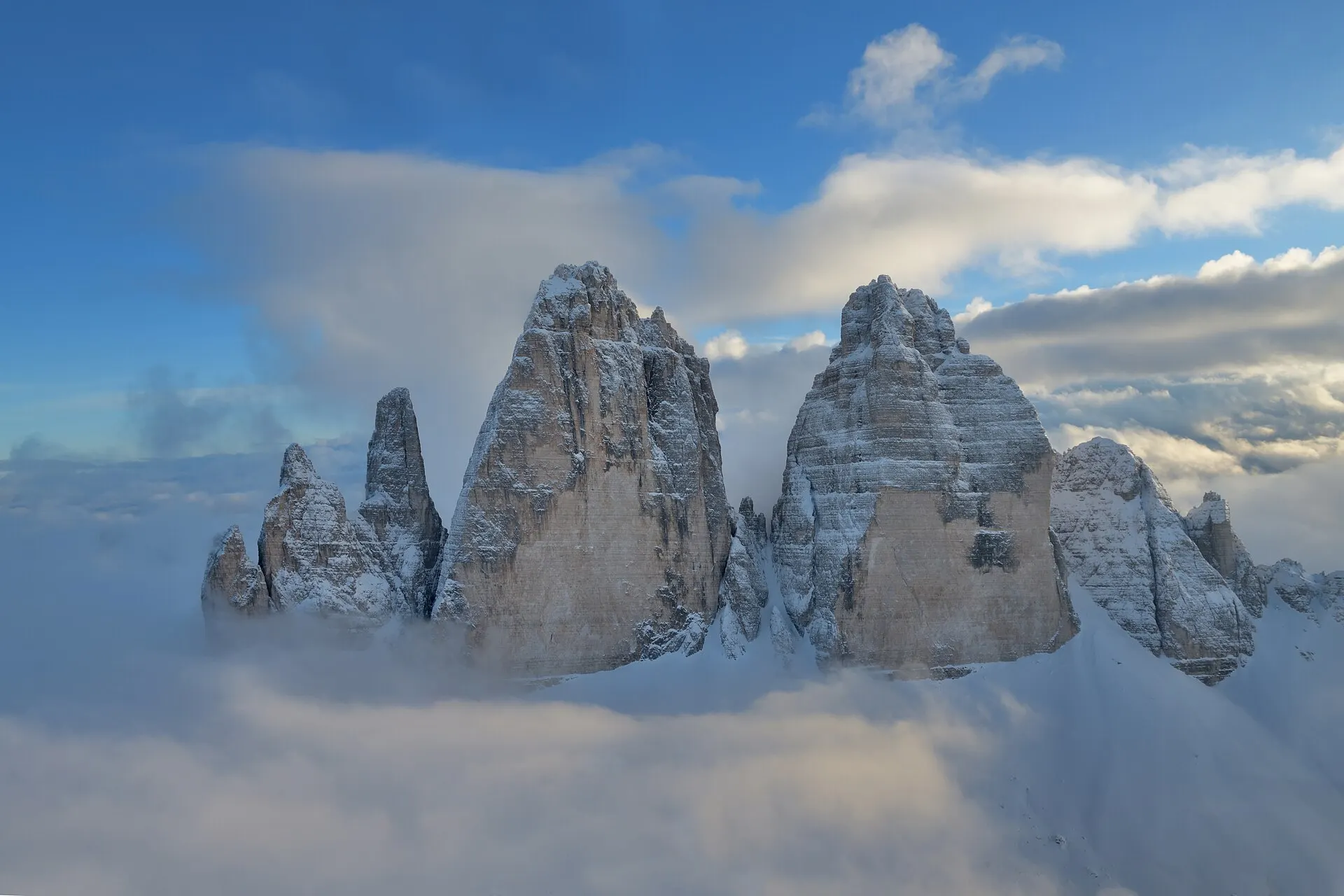 The Tre Cime di Lavaredo — three iconic dolomite peaks rising above a sea of clouds.
