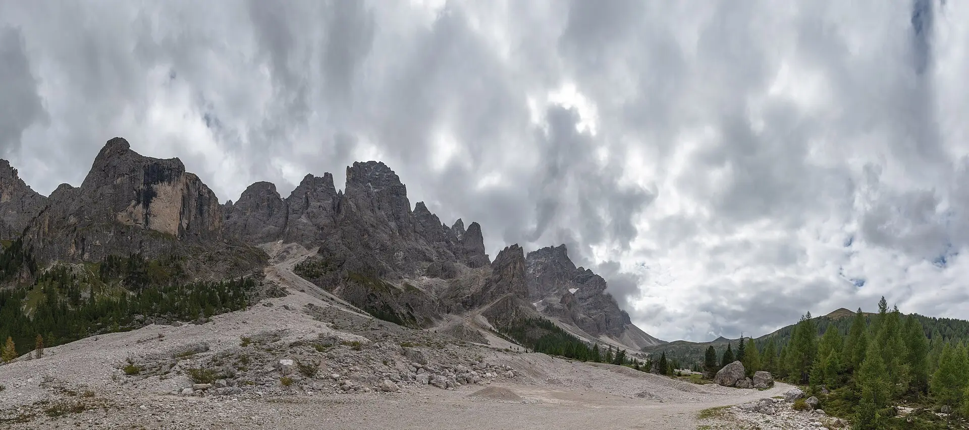 Val Venegia — the Pale di San Martino peaks rising behind a broad gravel valley floor under summer clouds.
