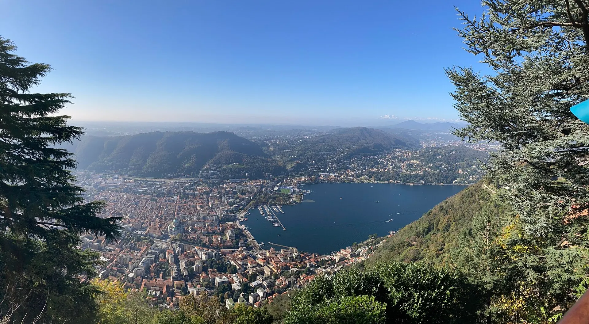 Panorama from Brunate above Como — the city, the lake's southern basin, and the surrounding hills.