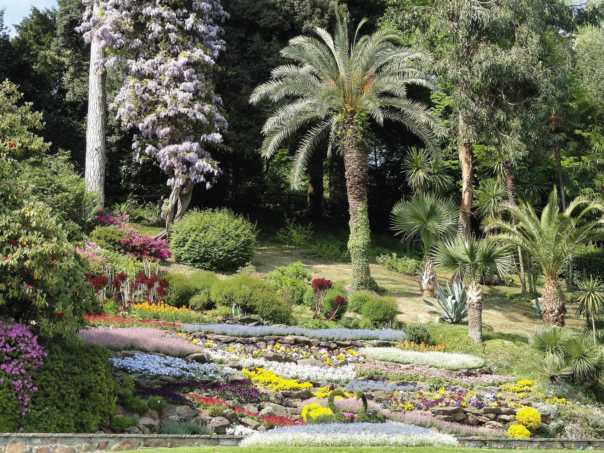 Villa Carlotta in Tremezzo — the botanical garden in spring with cascading flower beds, palms, and wisteria.