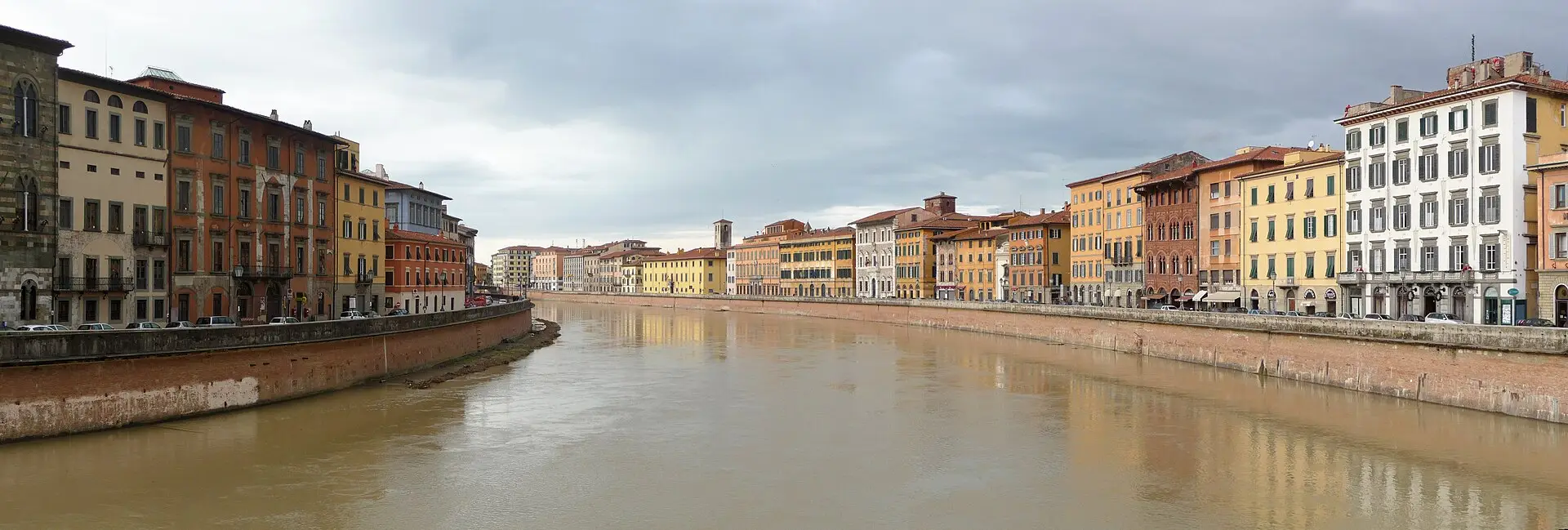 The Arno river in Pisa with the lungarni palazzi lining both banks under a moody sky.